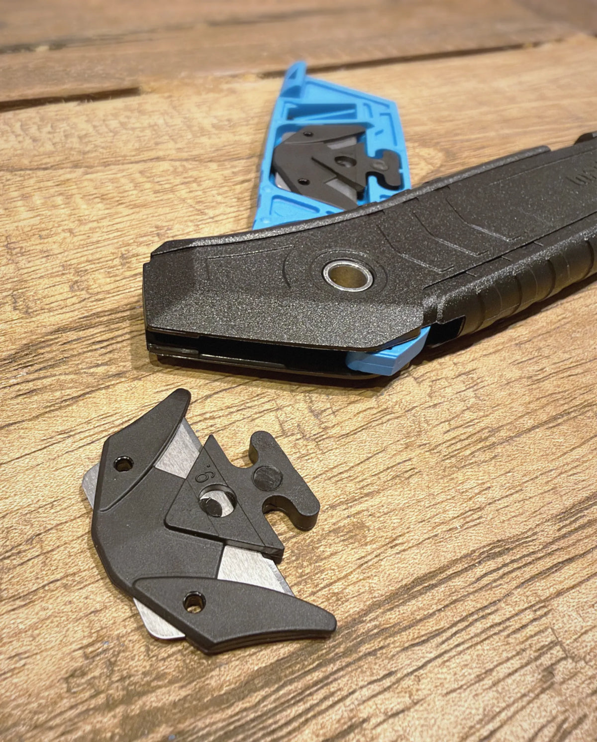 MARTOR SECUMAX 350 beim Klingenwechsel: geöffnetes Magazin mit Ersatzklinge und herausgenommener 2in1-Klingenkopf auf Holz – SICHERHEITSCUTTER.DE